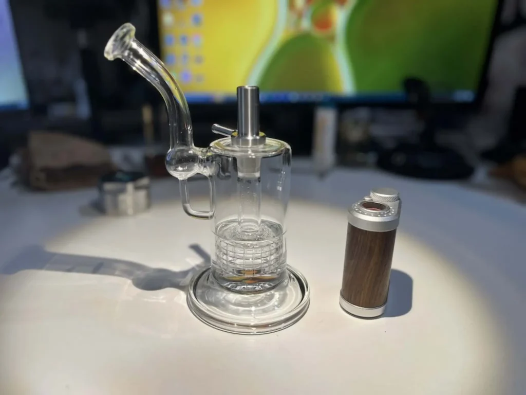 Glass bubbler with water pipe adapter attached, and the Tinymight 2 sitting next to it.