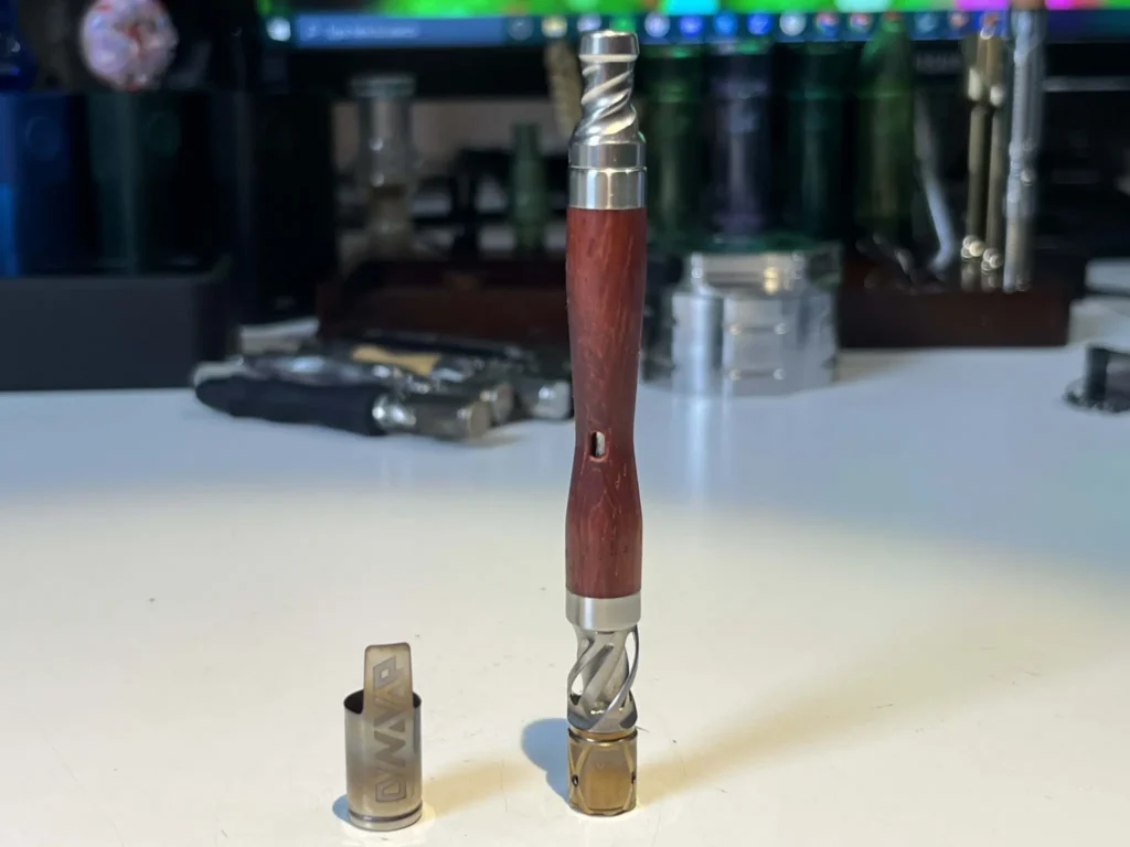DynaVap WoodWynd sitting on a desk with the cap removed and sitting to the side.